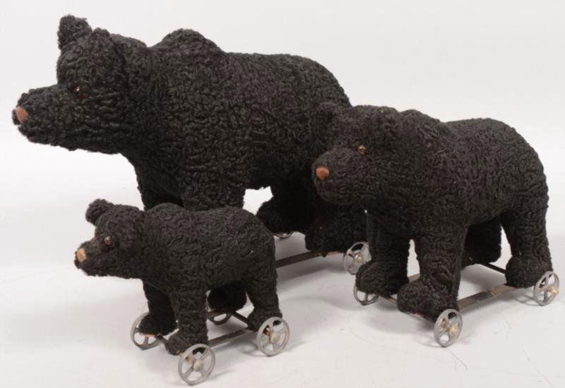 Three Graduated Toy Black Bear Pull Toys. Strap ir: Three Graduated Toy Black Bear Pull Toys. Strap iron frame with four cast tin spoked wheels. Bears have a curly lamb coat with brown thread nose and glass eyes. All signed on front paw pads: inM.E. Be