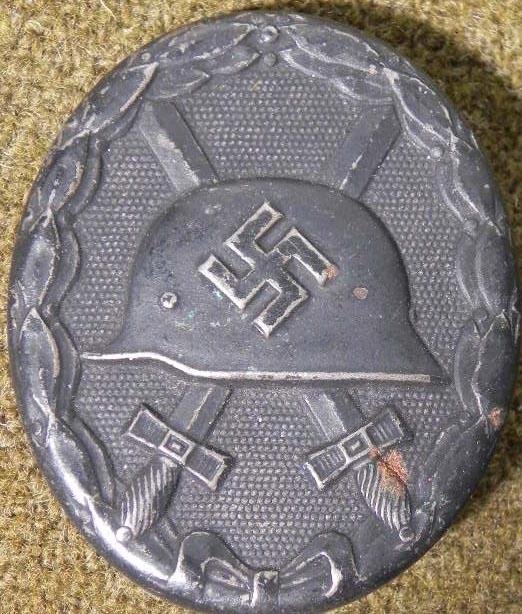 NAZI BLACK WOUND BADGE EARLY ORIGINAL: HERE IS AN EARLY ORIGINAL NAZI BLACK WOUND BADGE MARKED "L/56" WITH CRISP DETAIL. THE NAZI HELMET HAS A LARGE SWASTIKA WITH CROSSED SWORDS IN WREATH AND A TEXTURED BACKGROUND. *