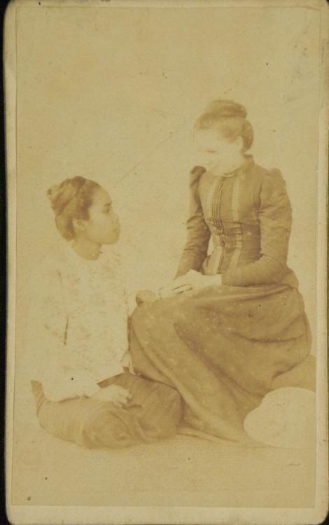 Antique CDV Photograph African American Woman: This antique Carte de Visite photograph is a studio shot of young African American Woman sitting beside an older Caucasian woman. Their relationship may have been one of servant, housekeeper, or caret