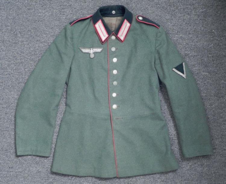 WWII Nazi NCO German Wehrmacht Artillery Jacket 1st Reg: This is a WWII era Nazi NCO German Wehrmacht Artillery Jacket. It is green with dark green felt collar and collar taps, both with red piping. The shoulder buttons have the number 1 for 1st regiment. T