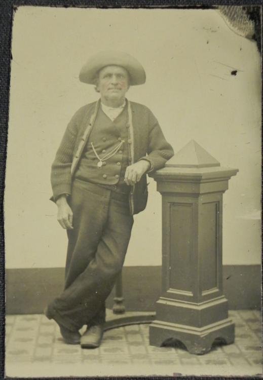 Antique Tintype Photograph Man w/Large Brim Hat: This antique tintype photograph is a studio portrait of a man in large brimmed hat, along with sweater and pocket watch on chain. The cheeks are lightly tinted. The size is 2 1/8 x 3 1/4 inches. The c