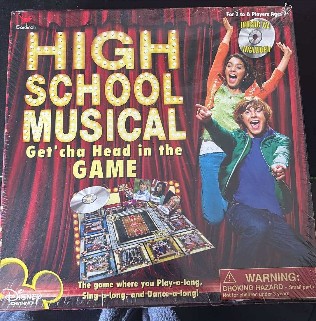 Disney Channel High School Musical Board Game “Get’cha Head in the Game?? (Music CD Included): Disney Channel High School Musical: “Get’cha Head in the Game” board game, shown in original packaging, designed for 2–6 players ages 7+ and advertised to include a music CD for interactiv