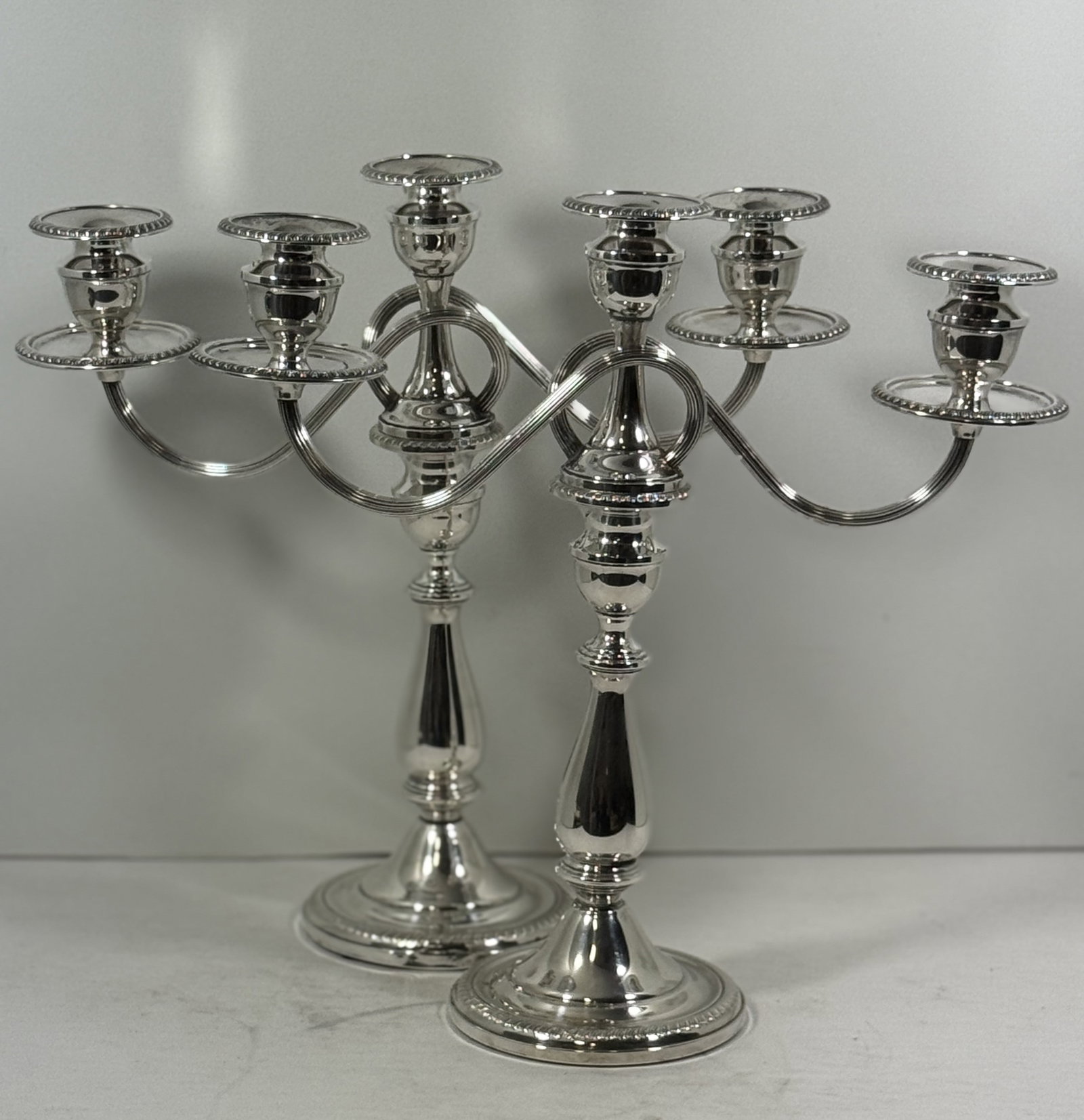 Pair of Sterling Silver Reinforced Convertible One to Three-Light Candelabras: Pair of American Sterling Silver convertible candelabra, each with detachable three-light branches. The design allows for versatility: used as tall single candlesticks or fitted with the scrolling thr