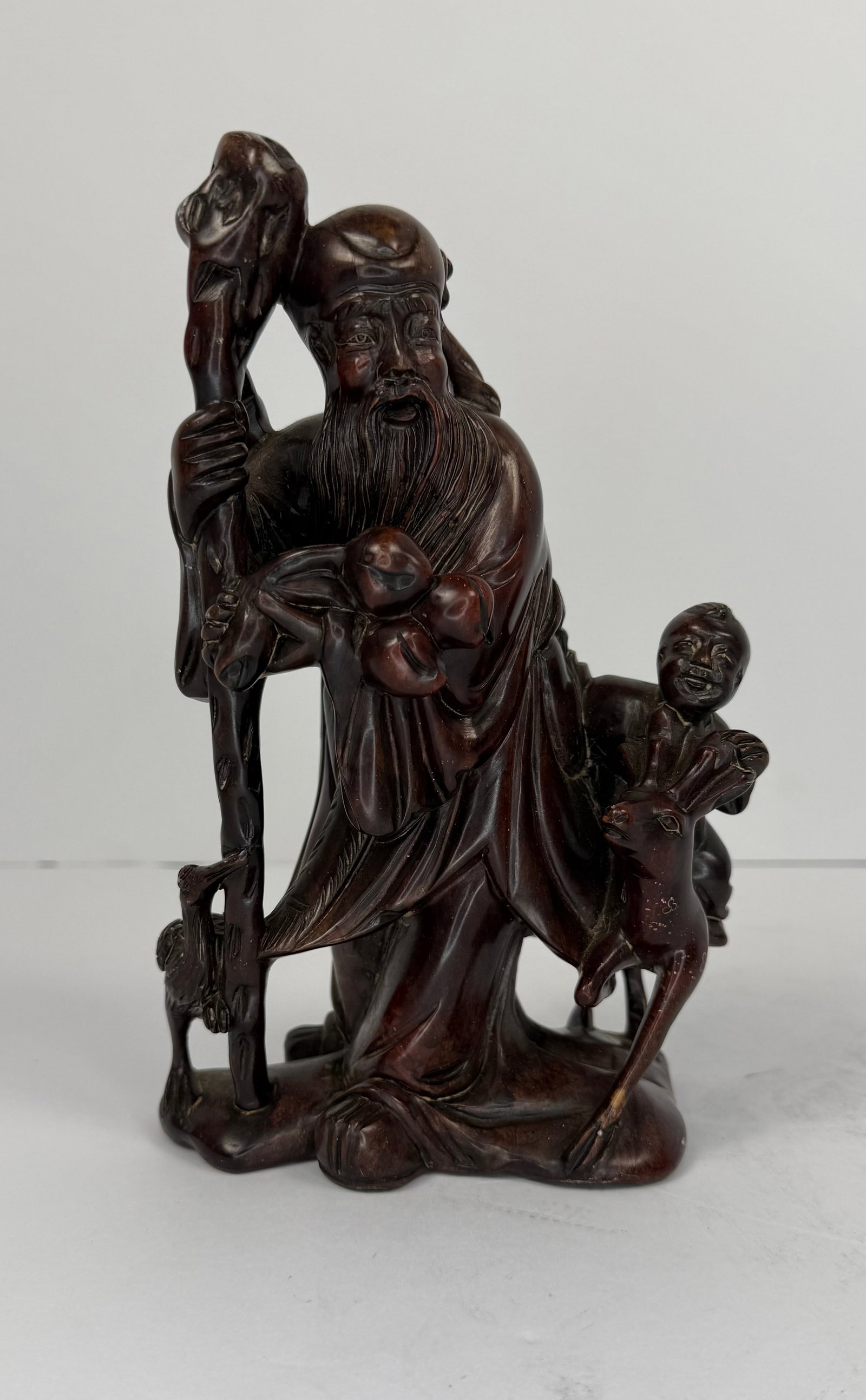 Vintage Carved Hardstone - Chinese Style Longevity Sculpture: A richly detailed carved figural sculpture depicting a standing Asian elder or immortal figure holding a staff, accompanied by a child attendant, deer, bird/crane, and fruit or peach-form motifs. The 