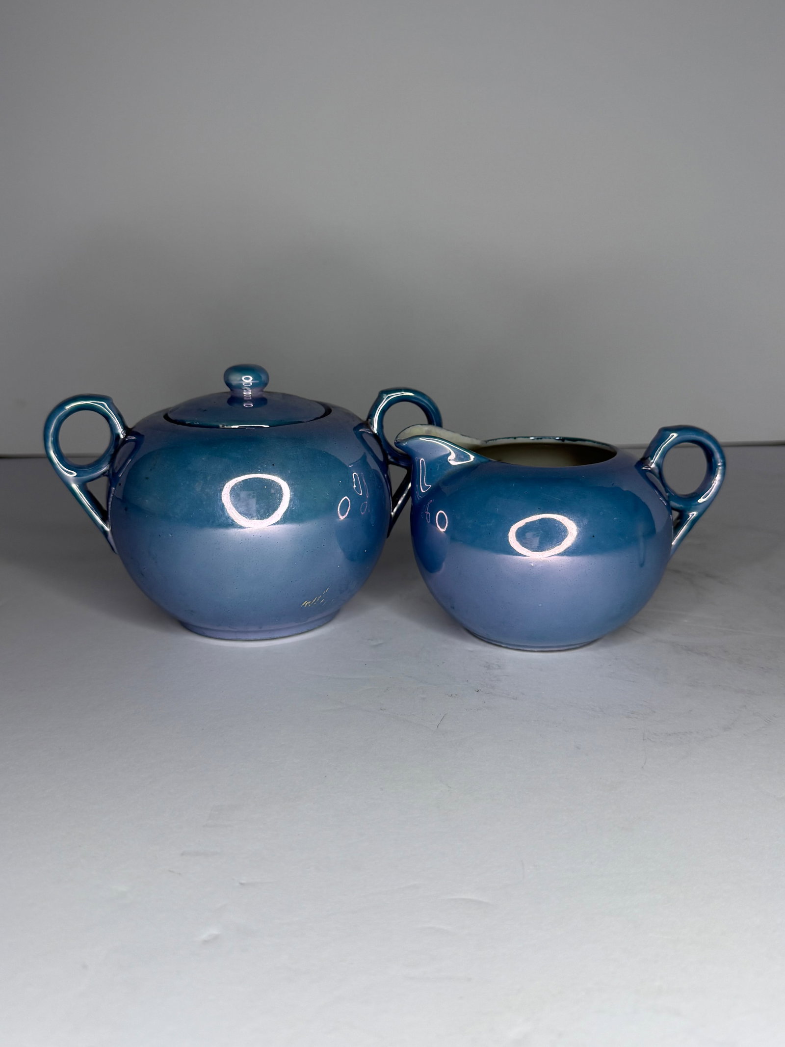 Vintage Japanese Blue Lustreware Cream & Sugar Set: A striking vintage Japanese ceramic cream and sugar set featuring a vibrant iridescent blue lustre glaze, exhibiting a soft, oil-slick sheen that shifts beautifully under light. The set includes a lid