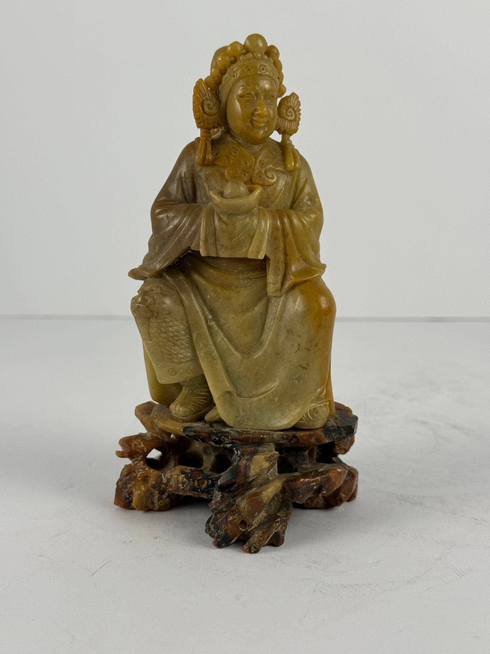 Chinese Carved Hardstone Figural Sculpture: A finely carved Chinese-style hardstone figural sculpture depicting a seated court figure or noble attendant, holding an ingot-form object in both hands, symbolizing prosperity and good fortune. The f
