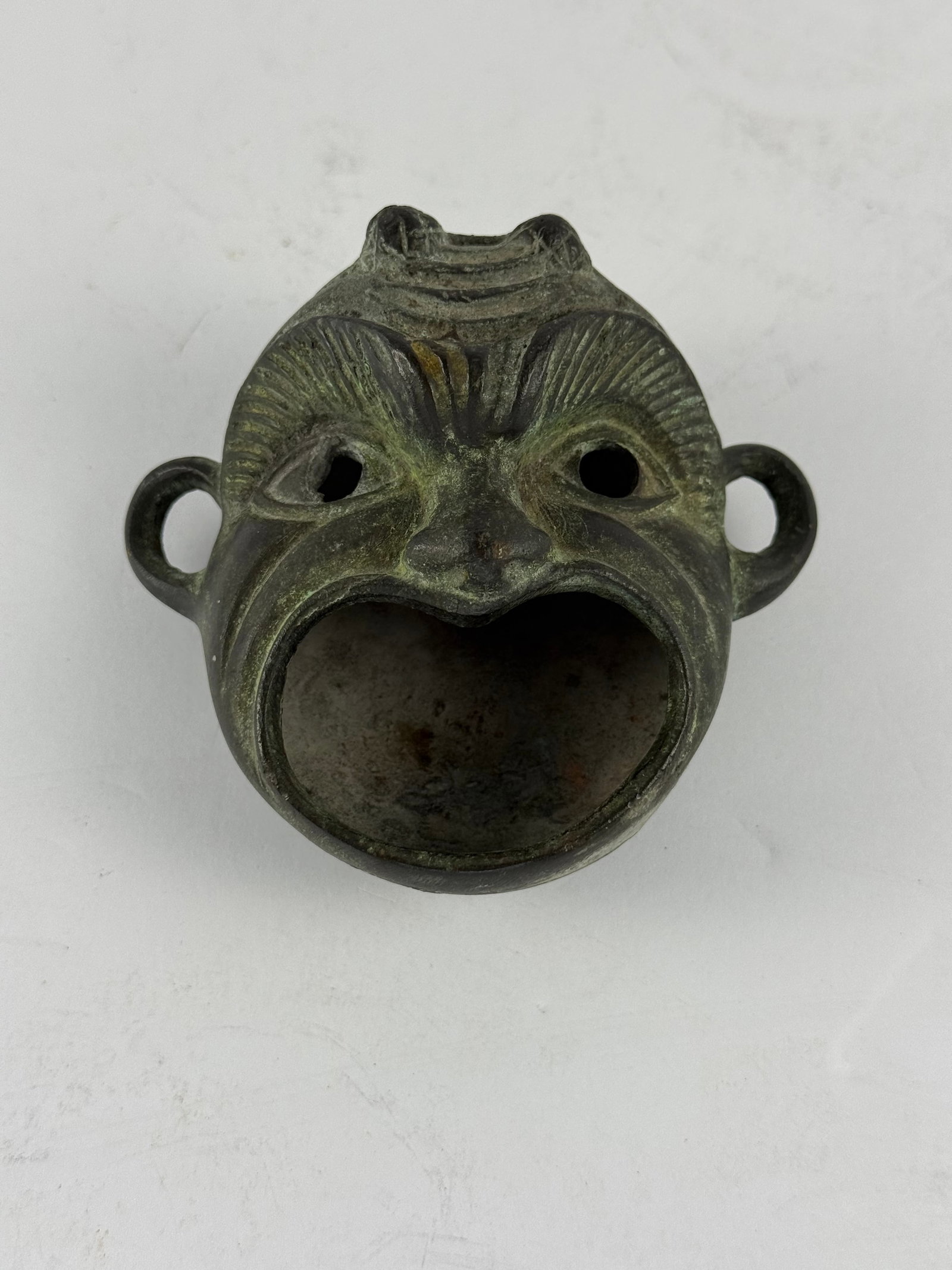 Chinese Style Cast Bronze Taotie Mask Figural Dish / Censer: A distinctive cast bronze figural vessel, modeled in the form of a stylized mask with pronounced eyes, arched brows, and a wide open mouth forming the bowl. The design draws inspiration from tradition