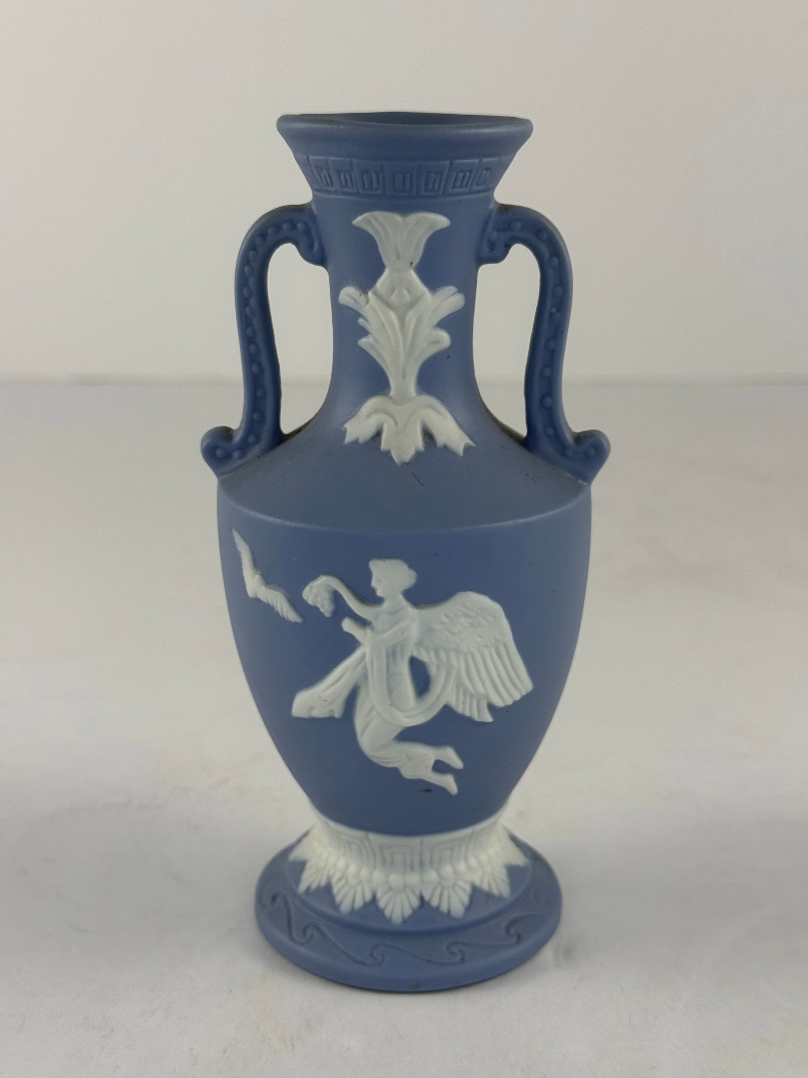 Wedgwood Style Jasperware Double Handle Amphora Vase: A finely modeled Wedgwood-style jasperware amphora vase, executed in a classic powder blue ground with applied white neoclassical relief decoration. The piece features a traditional double-handled for