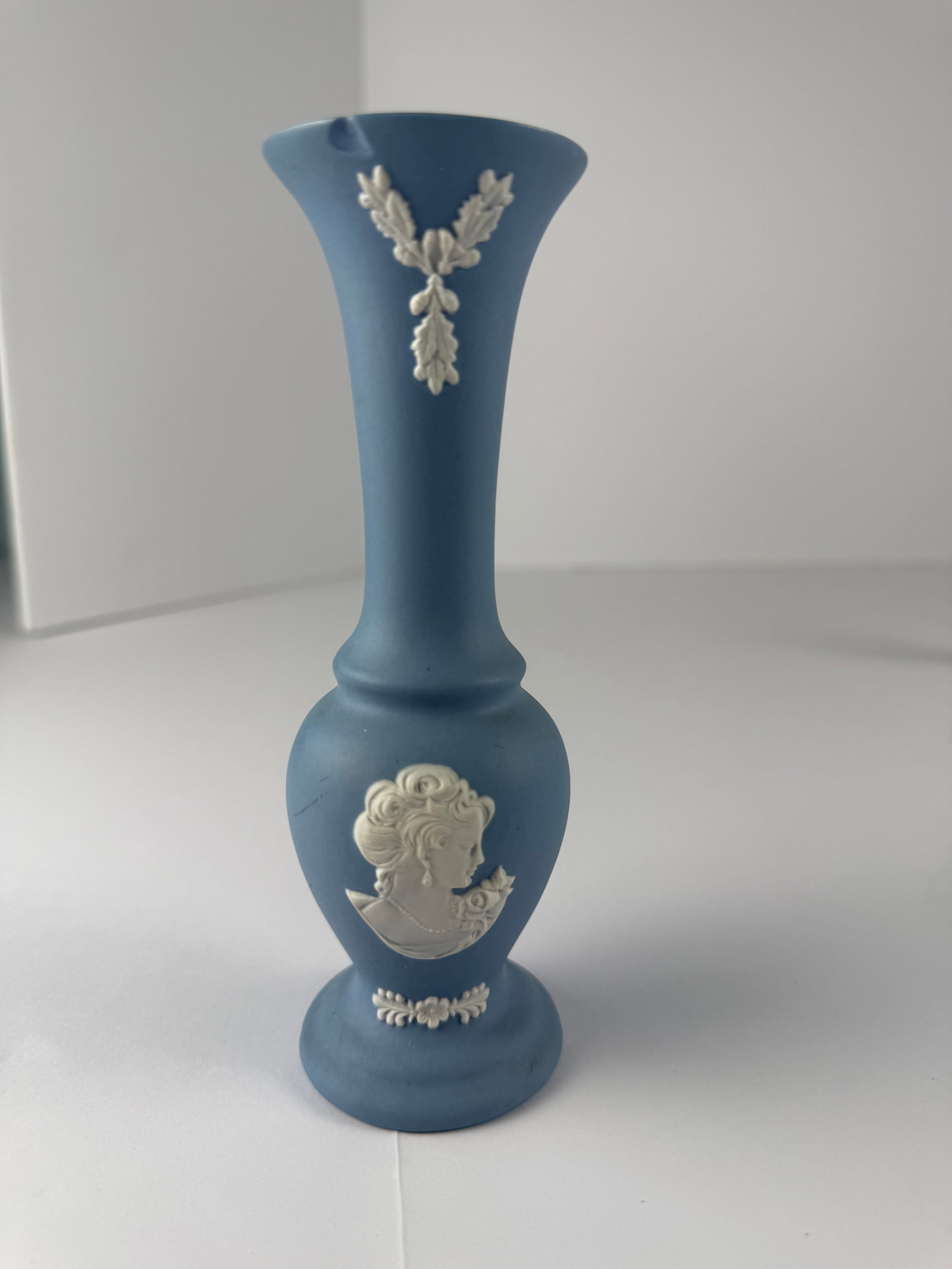 Blue Jasperware Style Bud Vase with Classical Cameo Relief, Wedgwood Inspired: A blue jasperware-style bud vase featuring applied white relief decoration in the Neoclassical manner, including a finely molded classical female cameo bust and foliate motifs. The vase is executed in