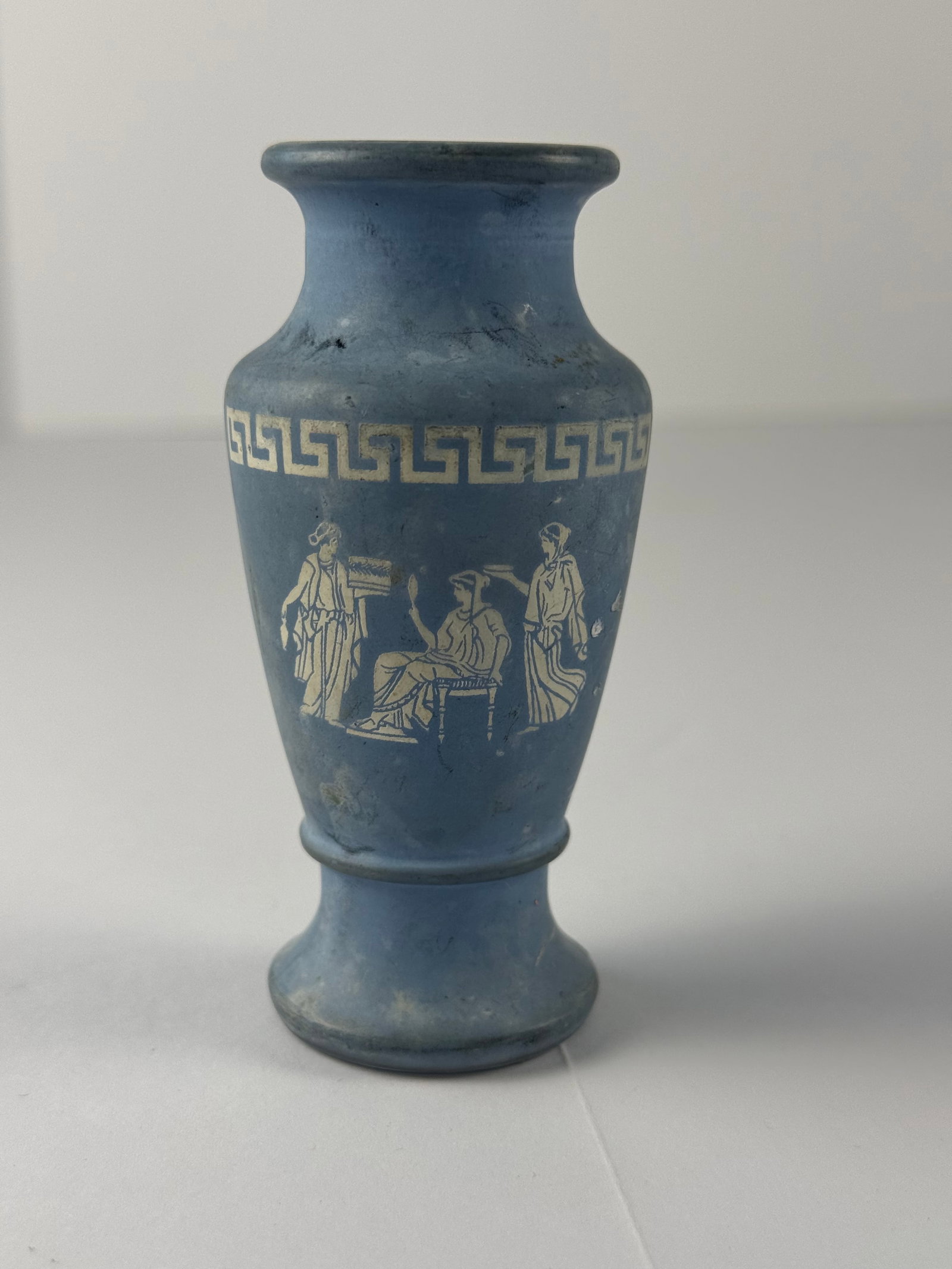 Vintage Grecian Style Glass Vase with Classical Figural Decoration: A vintage molded glass vase featuring white Grecian-style figural decoration and a continuous Greek key border motif around the upper body. The classical scene depicts draped figures in an ancient Gre