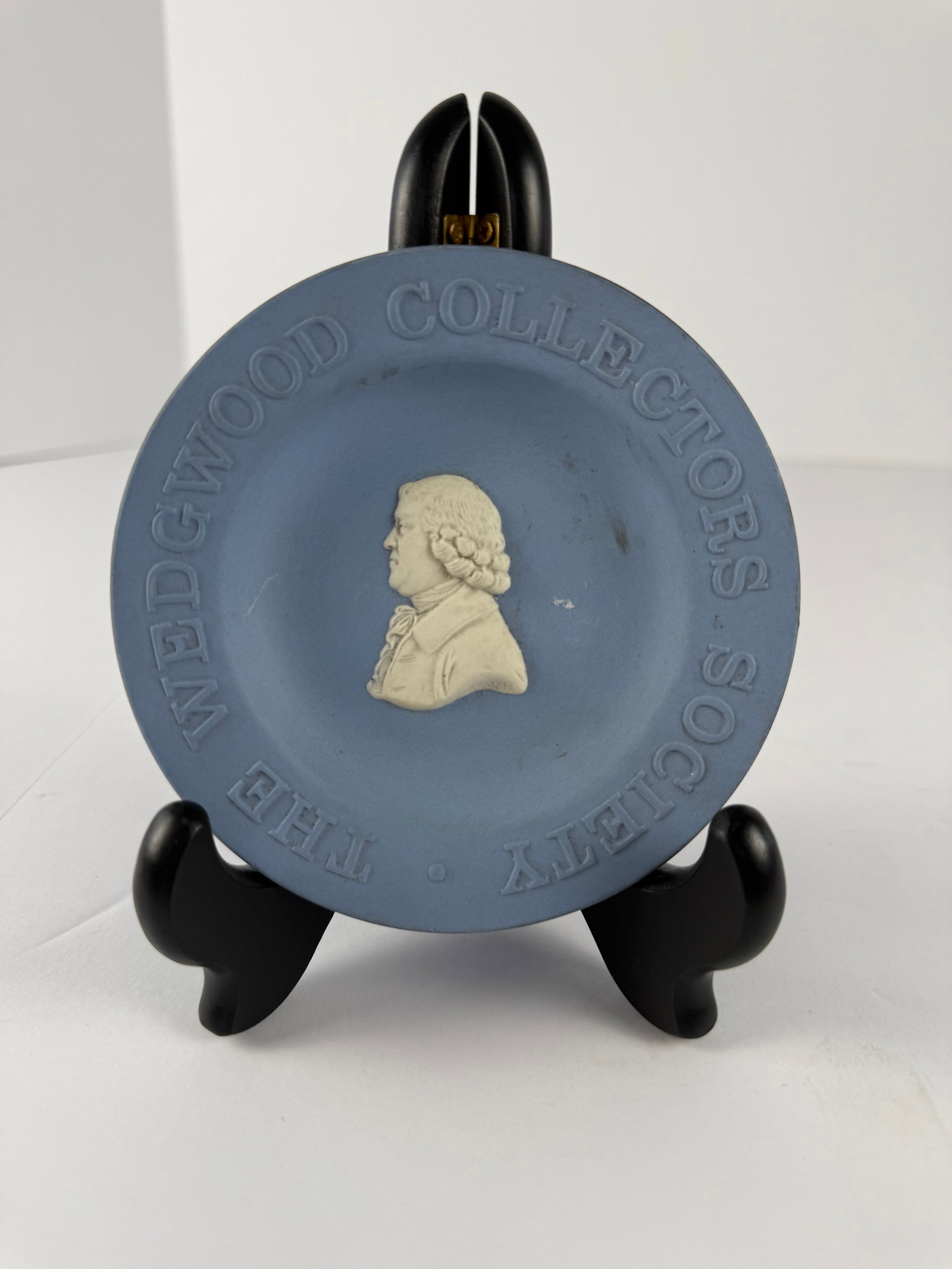 Wedgwood Collectors Society Blue Jasperware Plate: A vintage Wedgwood blue jasperware collectors plate featuring a raised white classical portrait bust at center surrounded by the embossed wording “THE WEDGWOOD COLLECTORS SOCIETY” around the r