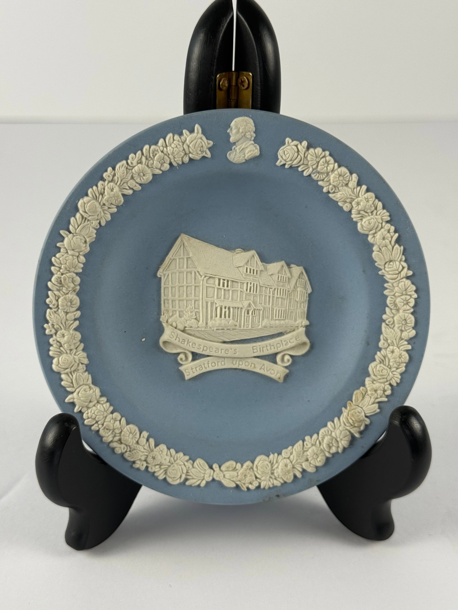 Wedgwood Blue Jasperware Shakespeare’s Birthplace Stratford Upon Avon Plate: A vintage Wedgwood blue jasperware decorative plate featuring a detailed white relief depiction of Shakespeare’s Birthplace in Stratford Upon Avon at center. The scene is framed by an ornate applied