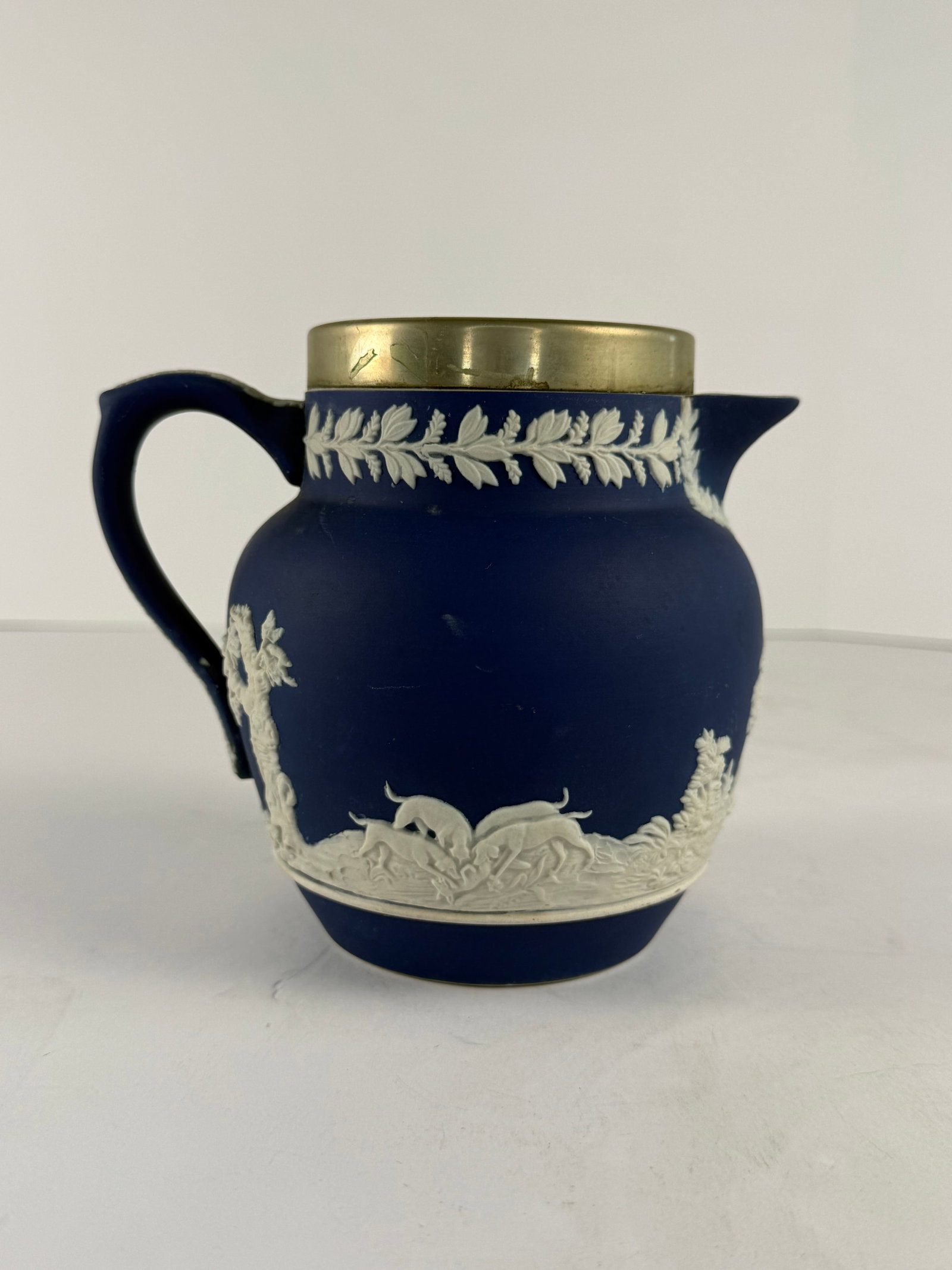 Adams Tunstall England Jasperware Pitcher: A vintage Adams jasperware pitcher featuring a deep cobalt blue matte ground with finely applied white relief decoration depicting classical hunting and pastoral scenes executed in the neoclassical ta