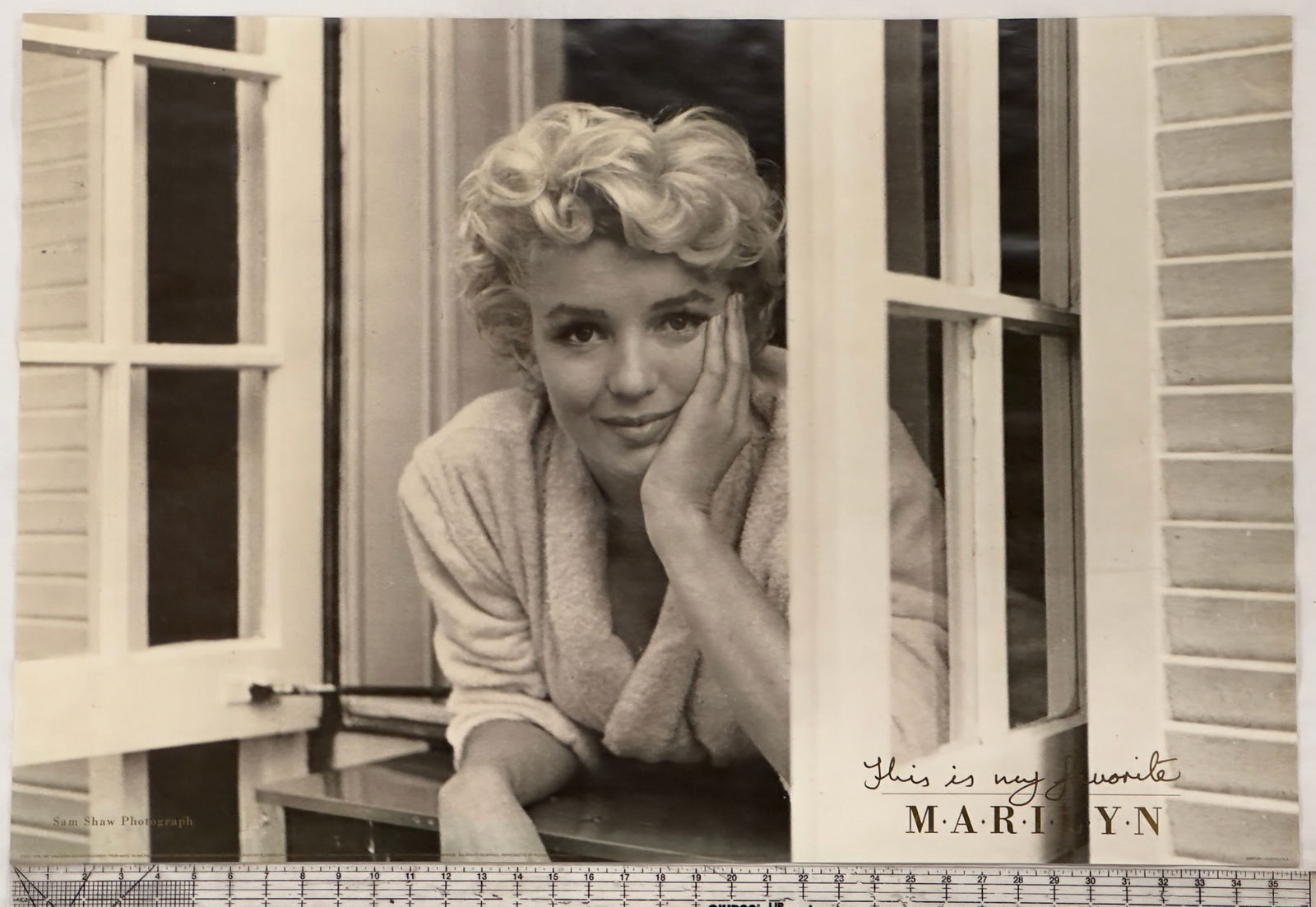 Vintage Sam Shaw Photograph of Marilyn Monroe Poster: This is a vintage black and white photograph of Marilyn Monroe, taken by renowned photographer Sam Shaw. The image captures Monroe in a candid moment, leaning out of a window with a relaxed expression