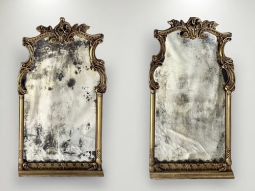 Pair of Antique Giltwood Rococo Style Mirrors: This exquisite pair of antique mirrors features ornate giltwood frames in the Rococo style, characterized by intricate scrollwork and floral motifs. The mirrors exhibit a beautifully aged patina, enha