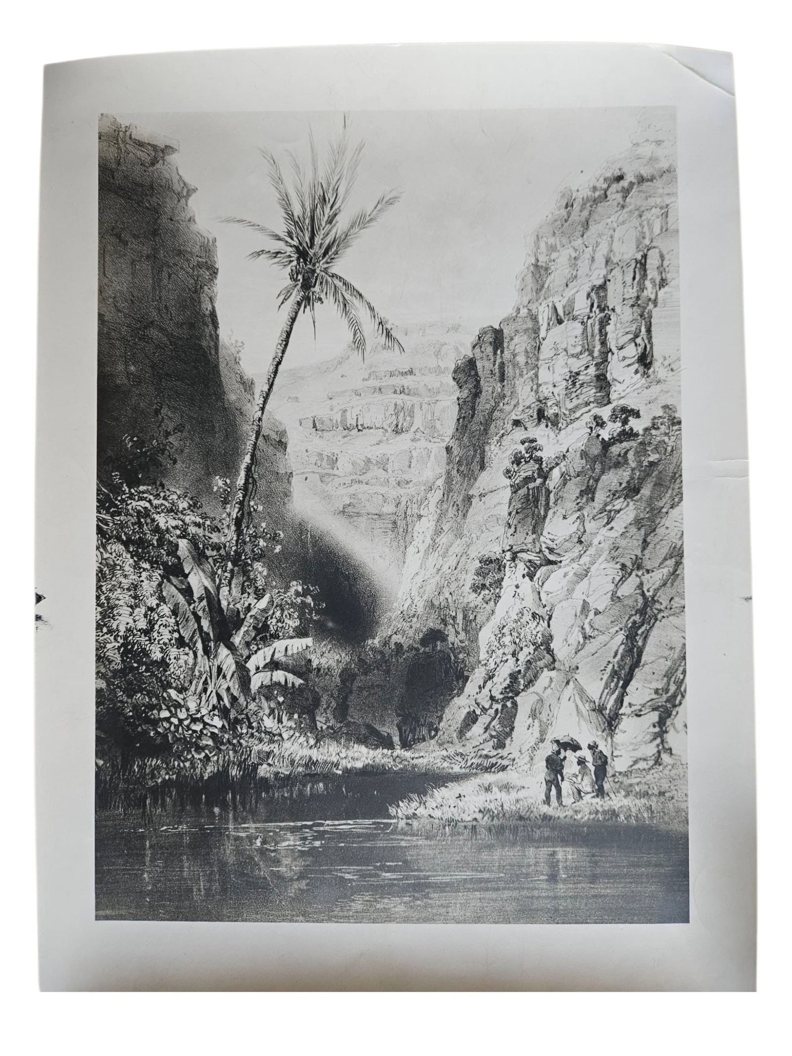 Orientalist Landscape with Palm Trees and Figures, Black and White Print on Paper: Black and white print on paper depicting a dramatic Middle Eastern or North African landscape with towering rocky cliffs, lush vegetation, a palm tree, water, and small figures in the foreground. Exec
