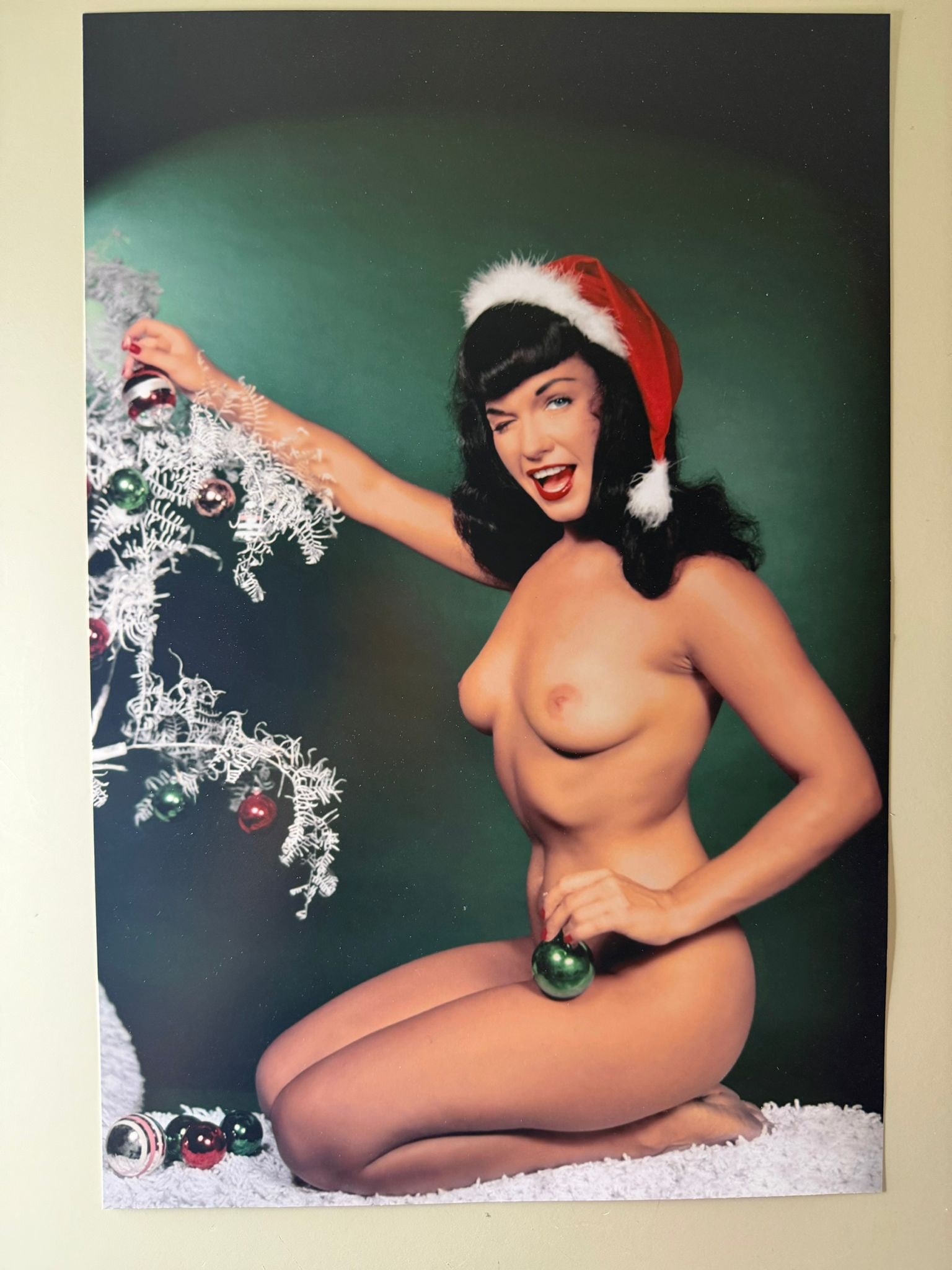 Bunny Yeager – Bettie Page Christmas Pin-Up, Vintage Hand-Signed Photograph: Original vintage photographic print by legendary American photographer Bunny Yeager, depicting the iconic pin-up model Bettie Page in one of her most recognizable Christmas-themed portraits. Wearing a