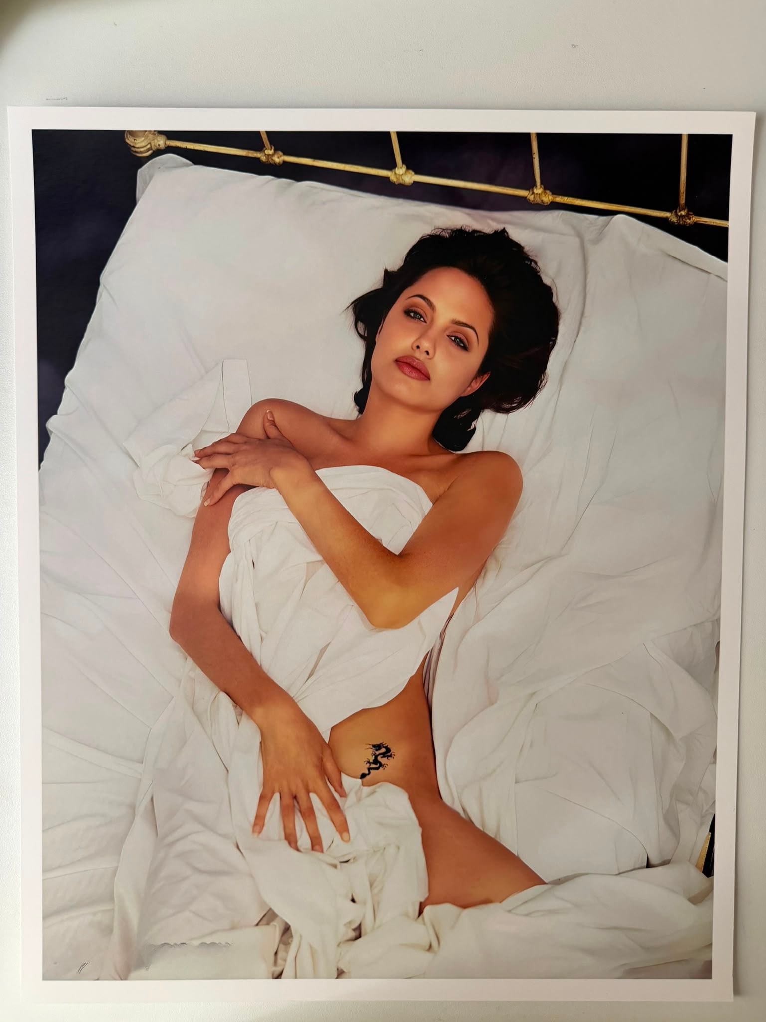Angelica Jolie – Iconic Bed & Dragon Tattoo Portrait (1990s Era) | Fine Art Photographic Print: Angelica Jolie (Hollywood Icon)Title: Bed Session with Dragon TattooMedium: Fine Art Silver Halide / Archival Photographic PrintDimensions: 38 x 32 cm (approx. 15 x 12.6 inches)Authentication (Verso):