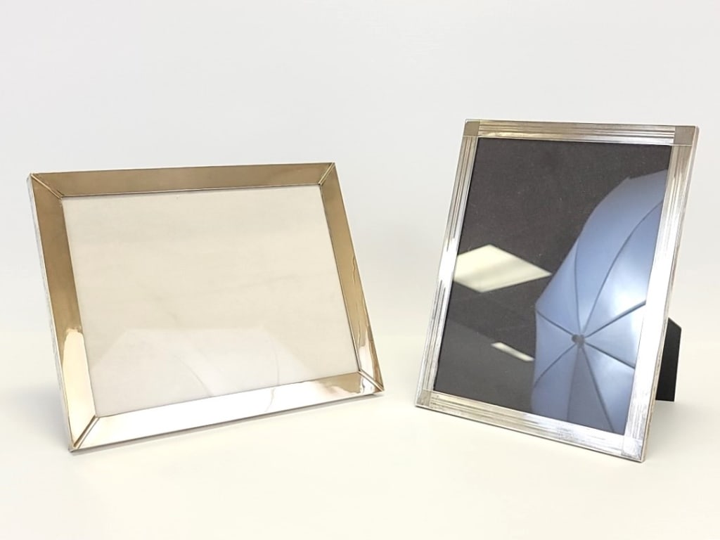 TWO STERLING SILVER PHOTO FRAMES: Lot of two large sterling silver photo frames. Includes an Inman frame for a vertical 7" x 9" photo, total size of the frame is 8" x 10" x .25" thick, backed with black acrylic. The second frame is st