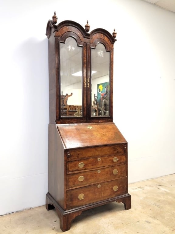 QUEEN ANNE BURLED WOOD BUREAU BOOKCASE: Queen Anne period burled wood bureau bookcase. Early 18th century. Two part construction, the top having a double front arched pediment crown with three acord style finials, doors with beveled glass i
