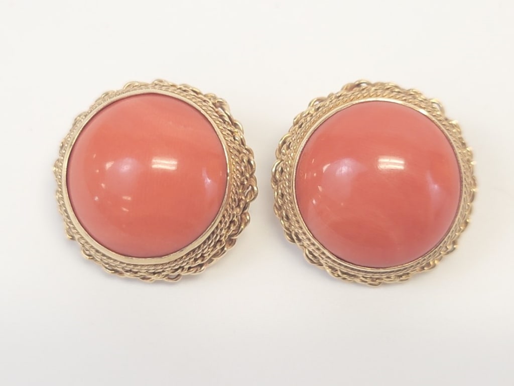 CORAL AND 14K YELLOW GOLD CLIP ON EARRINGS: CORAL AND 14K YELLOW GOLD CLIP ON EARRINGS: Large bezel set coral cabochon framed by a twisted rope work border mounted in 14k yellow gold. Condition is good and shows only minor surface wear consiste