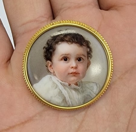 ANTIQUE MINIATURE PORTRAIT ON PORCELAIN, YOUNG BOY: Antique miniature portrait on porcelain depicting a young boy. Mounted in gold tone brooch setting. Measures a total of 1-3/8" diameter. Condition: good, see images. Weight: 13.4 grams.