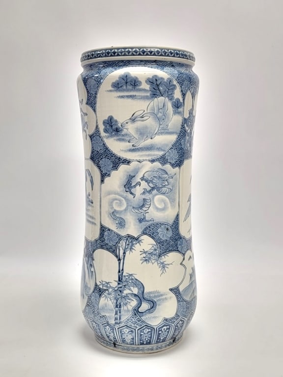 JAPANESE BLUE & WHITE PORCELAIN UMBRELLA CANE STAND: Japanese blue and white porcelain umbrella or cane stand. Painted with multiple panels each featuring different animals. Measures a total of 24.25" tall x about 10.5" diameter. Condition: early staple