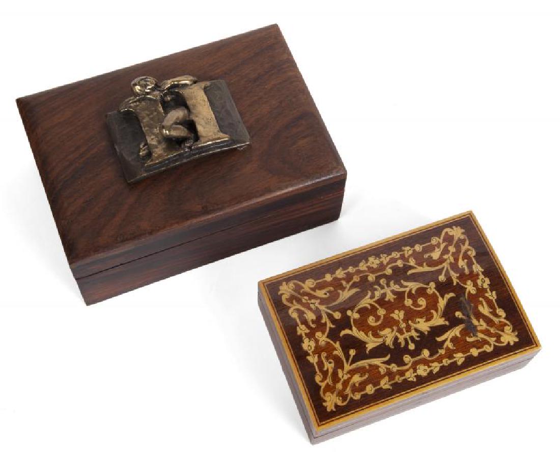 HUGH HEFNER DECORATIVE BOXES: Two decorative boxes, one with inlaid wood, the other topped with a brass ""H"" and a nude woman, marked ""Frederick Arnold of Encino."" Largest, 6 by 4 inches PROVENANCE From the Collection of Hugh M