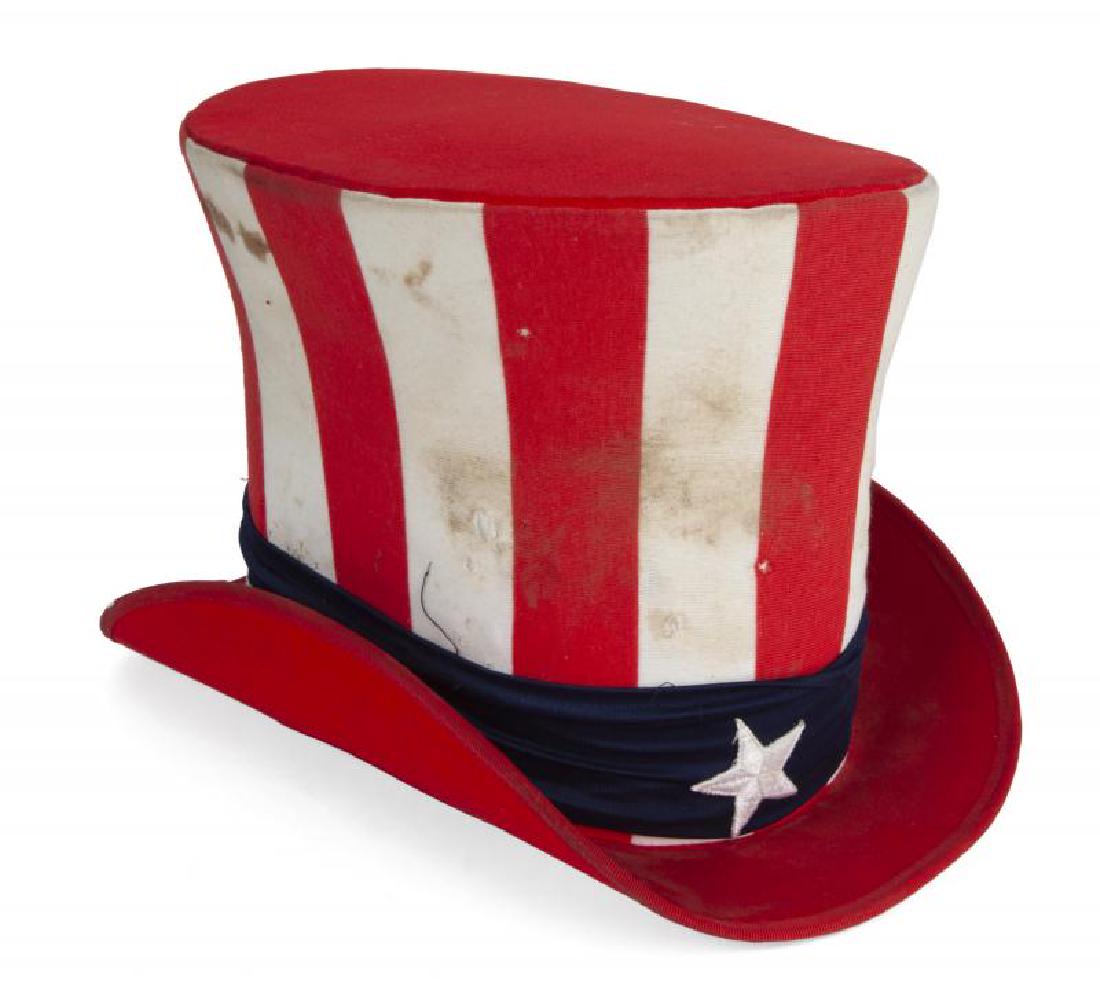 SLASH RED, WHITE AND BLUE HATS: A group of four hats: a stiff stars and stripes top hat, size L; two soft Uncle Sam top hats; and a tall soft Union Jack hat. PROVENANCE From the Collection of Slash and Perla Hudson Slash