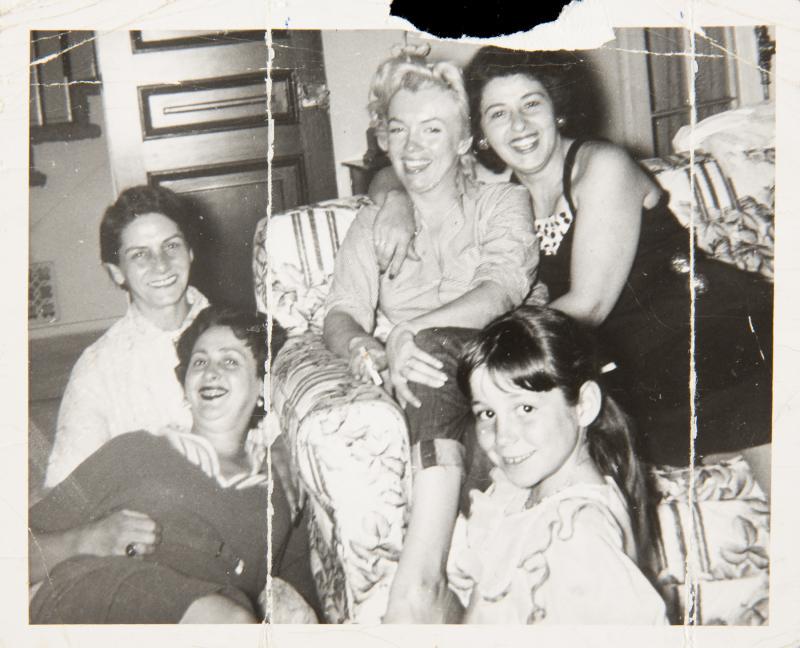 MARILYN MONROE BLACK AND WHITE SNAPSHOT: An original print with a glossy finish, though now creased and wrinkled, depicting the star in a living room with four other females circa 1954, a black ballpoint ink annotation handwritten on the ver
