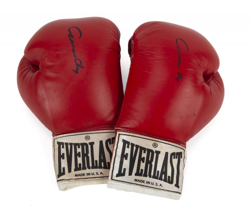 CASSIUS CLAY SIGNED BOXING GLOVES PAIR: A pair of red Everlast boxing gloves with white laces signed by former Heavyweight champion Muhammad Ali, formerly known as Cassius Clay, on the top of each glove in black marker. Before converting to
