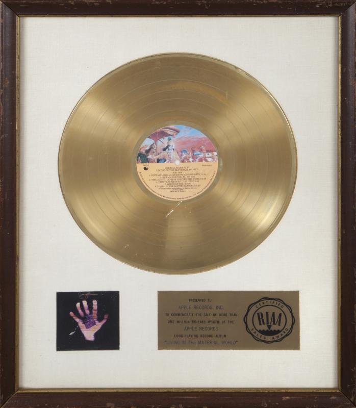 GEORGE HARRISON WHITE MATTE RECORD AWARD •: An RIAA-certified "gold" record award, white linen matte, presented to Apple Records to commemorate the sale of more than $1 million worth of George Harrison's long-playing record album Living in the