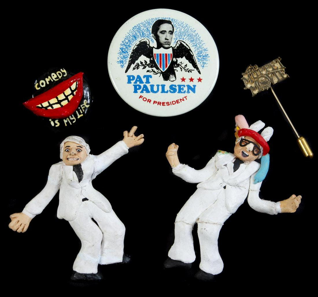 STEVE MARTIN LAPEL PINS: A group of five lapel pins including: a round button with text reading "Pat/ Paulsen/ For President"; a handmade clay brooch reading "Comedy/ Is My Life"; a gold-tone stick pin reading "The Muppet Mov