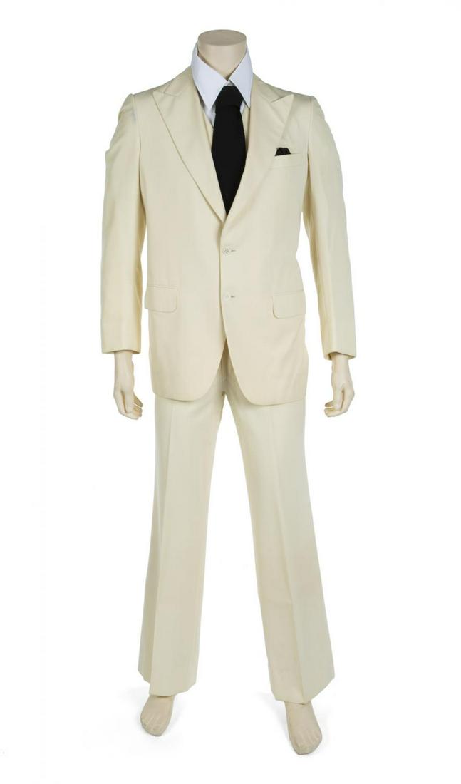 STEVE MARTIN TRADEMARK 1970s-ERA WHITE SUIT: A three-piece suit ensemble comprising an eggshell white blazer, peaked lapels, three front pockets, two-button front closure, lined in white satin with a repeating pattern reading "Brioni/ Roma," lab