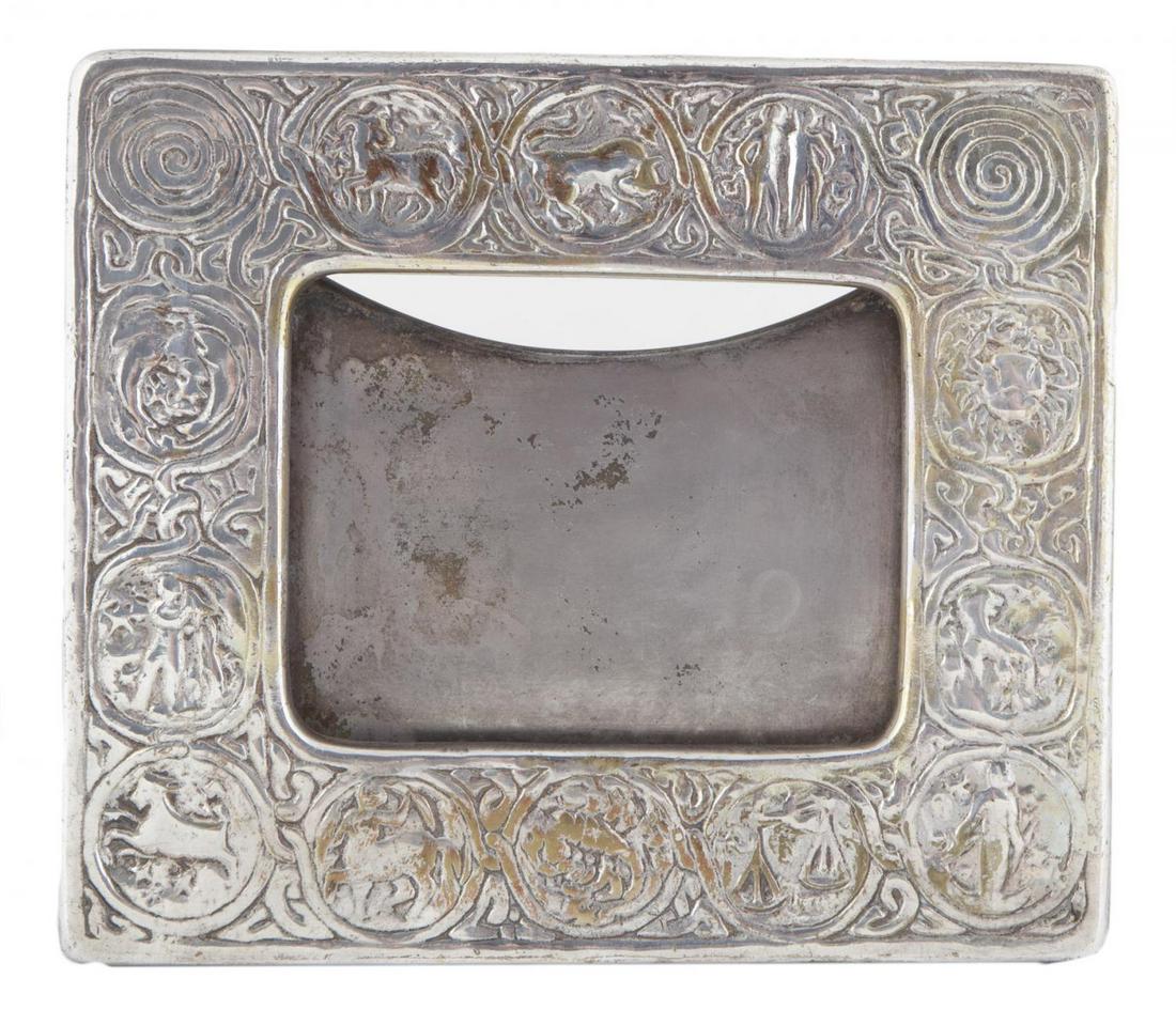 ROBERT EVANS TIFFANY STUDIOS ZODIAC PICTURE FRAME: An early 20th century embossed bronze frame with signs of the zodiac, marked "Tiffany Studios/New York/943" on the verso. 7 1/4 by 8 1/4 inches PROVENANCE From the Estate of Robert Evans Hollywood