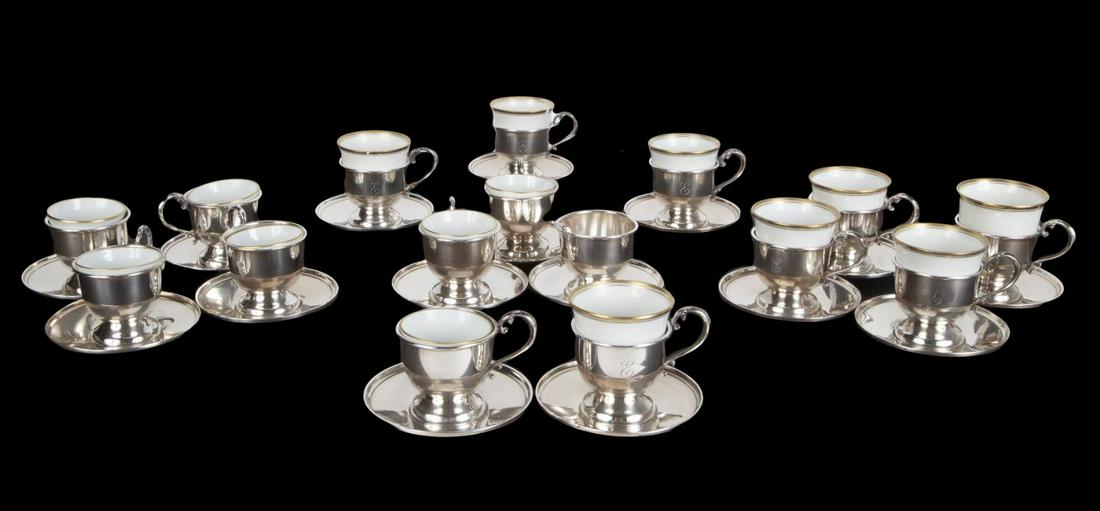 ROBERT EVANS CARTIER MONOGRAMMED DEMITASSE CUPS: A group of 10 Cartier "E" monogrammed and 6 non-monogrammed sterling demitasse cups, together with 9 gilt-rimmed Heutschenreuther and 7 Bernardaud Limoges porcelain liners. Sterling weight, 31.36 troy