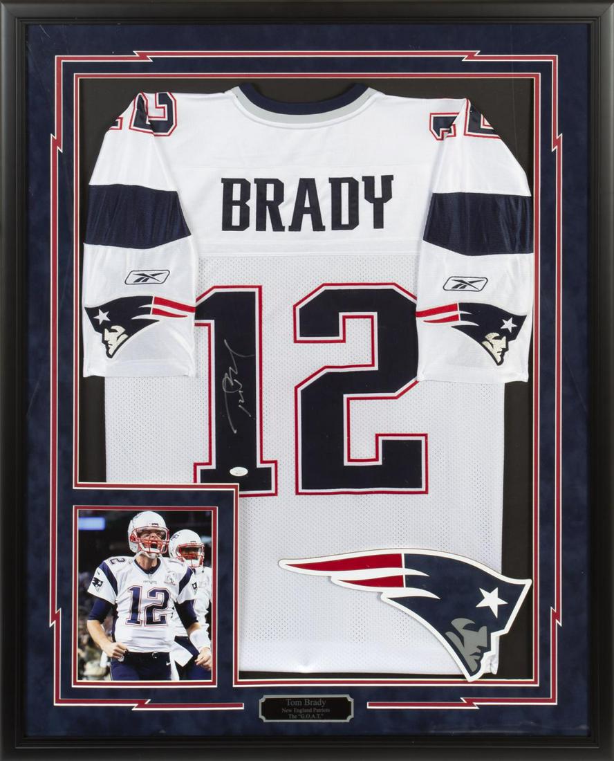 TOM BRADY NEW ENGLAND PATRIOTS SIGNED JERSEY: A Reebok brand New England Patriots jersey signed by Tom Brady in silver marker. The jersey features “Brady/ 12” to the back. Size 54. Framed together with a color image of Brady. Accompan