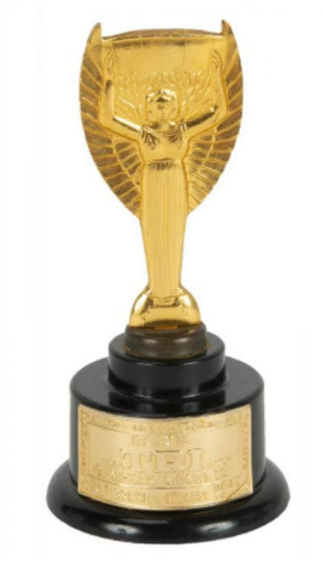 1970 WORLD CUP MINI SOUVENIR TROPHY: A mini souvenir trophy commemorating Brazil’s third participation in the World Cup. A plaque affixed to the trophy reads “Brasil/ Tri Campeao Mundial 1930-1970” with additional game 