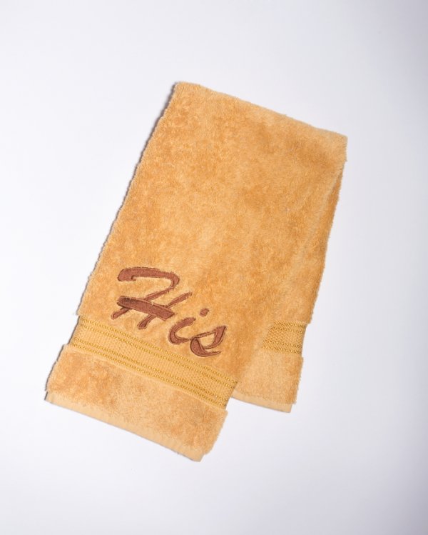 TOWEL FROM "PLAYBOY" PHOTOSHOOT: Gold bath towel, embroidered "His," used in a Playboy photo shoot with Divini Rae, the first Playmate of the Year from Alaska. The photographs ran in the November 2003 issue of Playboy. Accompanied by