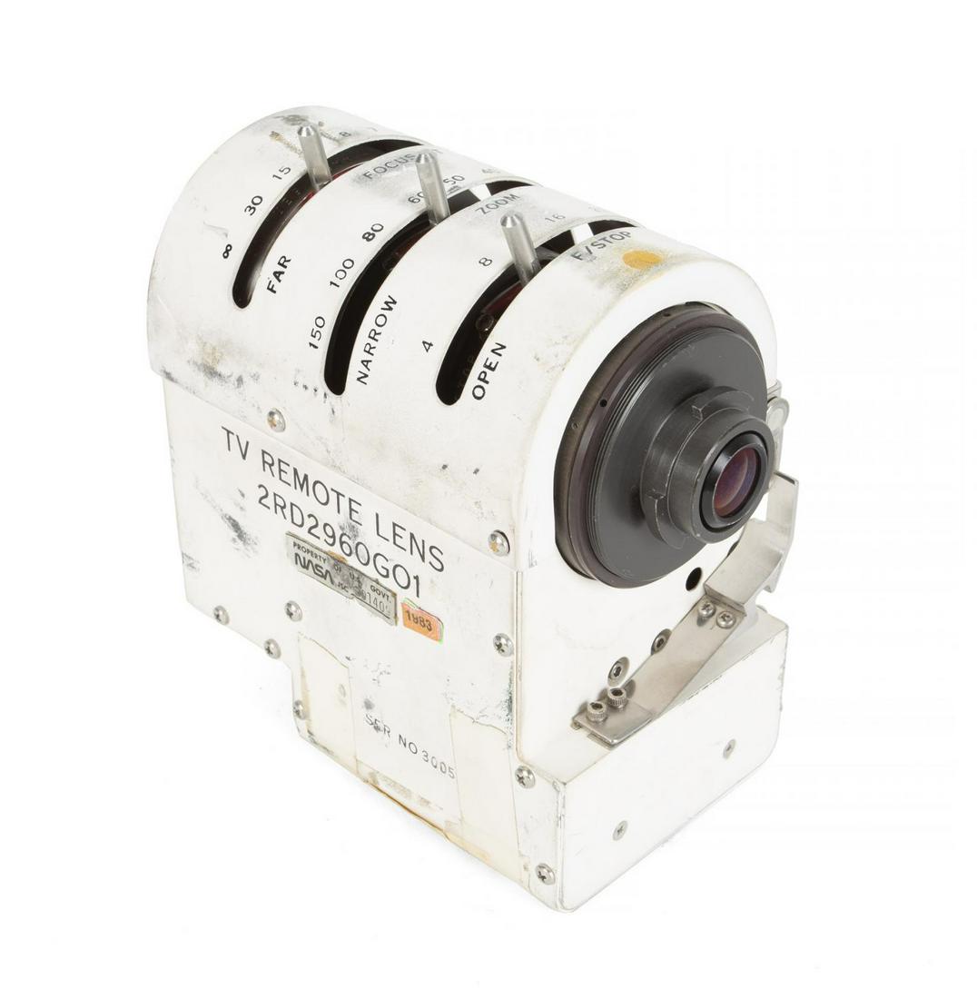 NASA LUNAR ROVER TV LENS ASSEMBLY: A television camera lens assembly (labelled: TV Remote Lens) of the type used by NASA on the lunar rover (LRV) during the later Apollo moon landing missions. The lens assembly is affixed with numerous