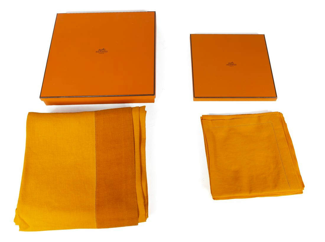 HERMES ORANGE TABLE LINENS: A tablecloth and eight matching linen napkins by maker Hermes. In presentation boxes. 95 by 68 inches Box, 3 1/2 by 12 1/2 by 12 1/2 inches Fine Art