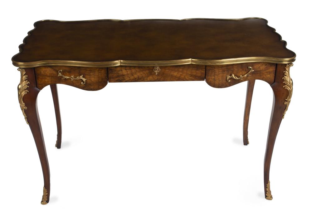 JEAN AND CASEY KASEM LOUIS XV STYLE BUREAU PLAT: A wood and parcel gilt Louis XV style bureau plat with a shaped faux leather top and bronze d'ore mounts, marked "Made in Vietnam." 30 x 48 x 24.5 inches PROVENANCE From The Collection of Jean and Cas