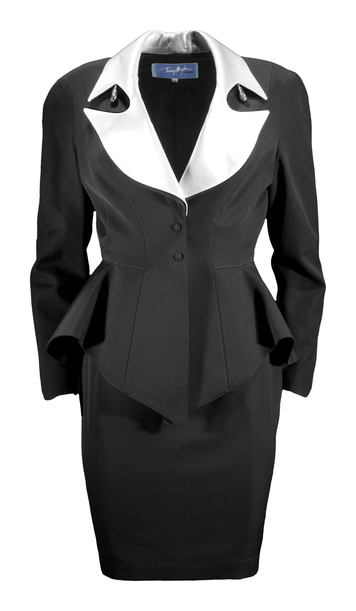Thierry Mugler | 1992 Skirt Suit: Lot 82: Thierry Mugler | 1992 Skirt Suit A Thierry Mugler black wool skirt suit with white satin lapel and cuffs from the Fall/Winter 1992 collection. Beautiful fitted peplum blazer with white satin n