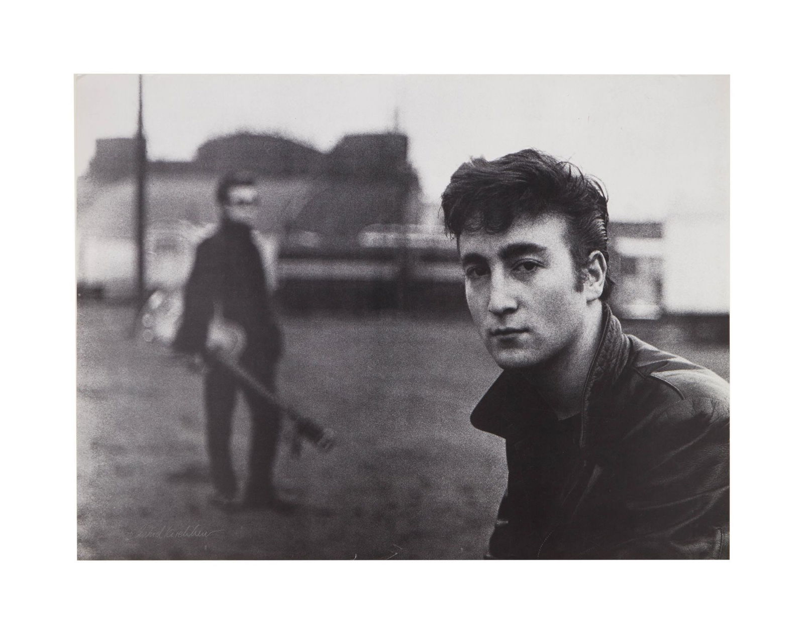 The Beatles | Astrid Kirchherr Signed John Lennon in Hamburg Limited-Edition Print: A black and white print of John Lennon from an image taken by the photographer Astrid Kirchherr in Hamburg in 1960. It shows John looking to the camera in the foreground with Stuart Sutcliffe in the b