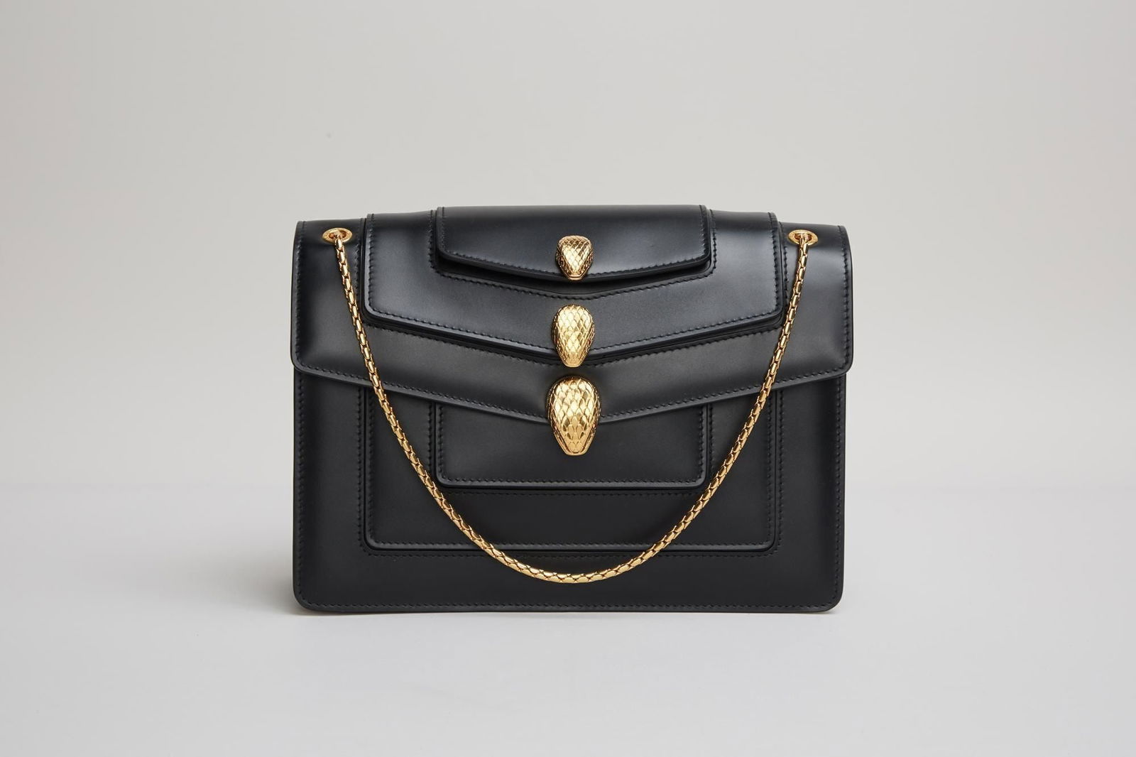 Bvlgari | Alexander Wang Serpentini Forever Handbag: An Alexander Wang x Bvlgari black calf leather shoulder bag with gold plated hardware. The east/west design features three overlaying flaps each with an etched metal snake head. Wang creates a unique