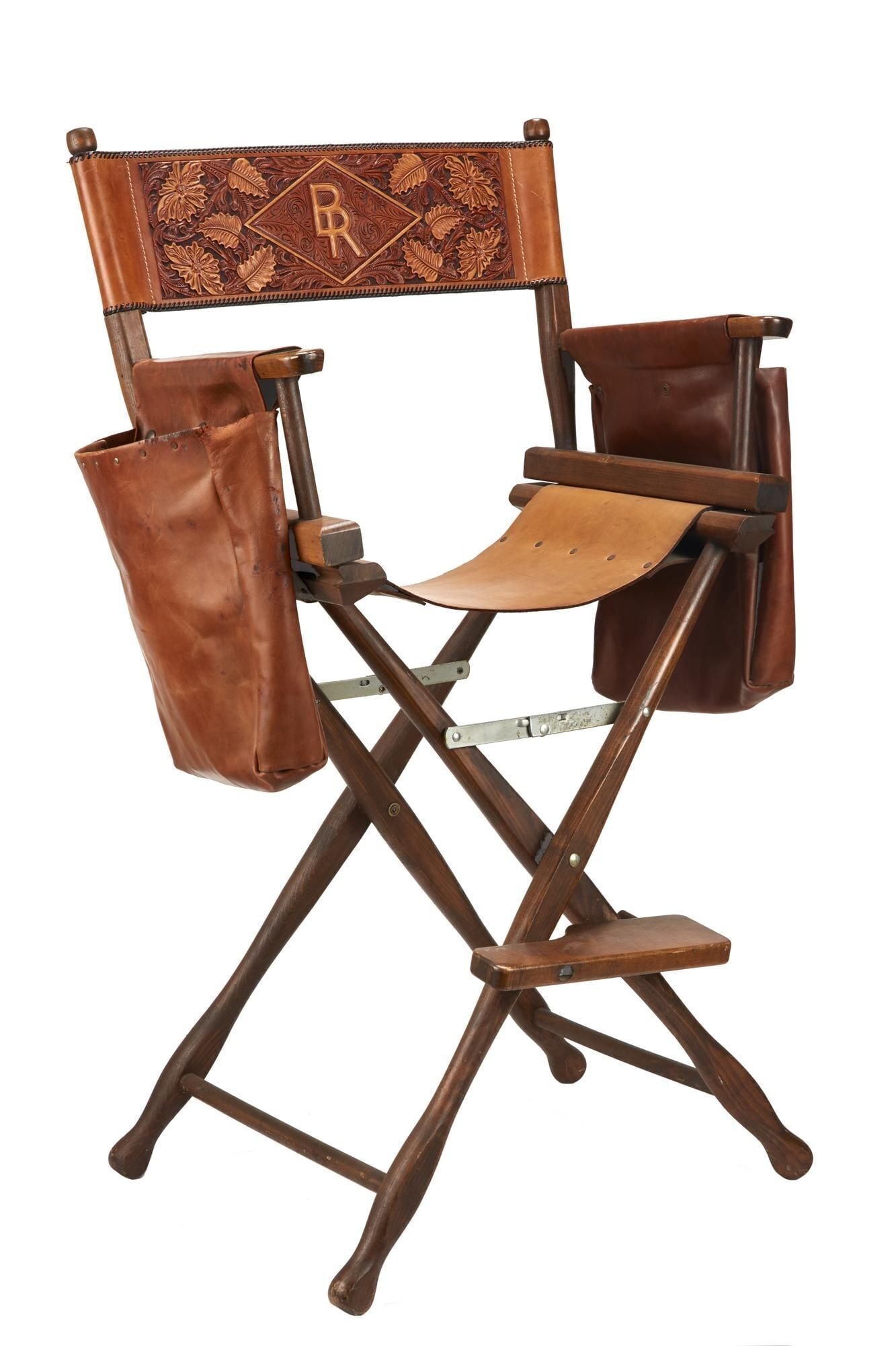 Burt Reynolds | Edward Bohlin Director's Chair: A wood-frame director's chair with tooled Edward Bohlin leather back, seat, and removable arm pouches. The chair back is monogrammed "BR" on one side and "Burt Reynolds" to the outside. The chair seat