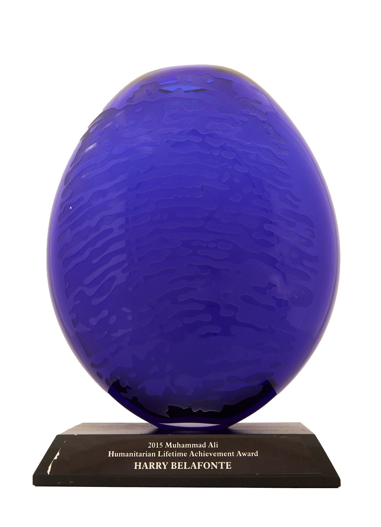 Harry Belafonte | Muhammad Ali Humanitarian Lifetime Achievement Award: A Muhammad Ali Humanitarian Lifetime Achievement Award presented to Harry Belafonte in 2015. The award features a cobalt blue glass vessel with the thumbprint of Ali enlarged to create an abstract pat