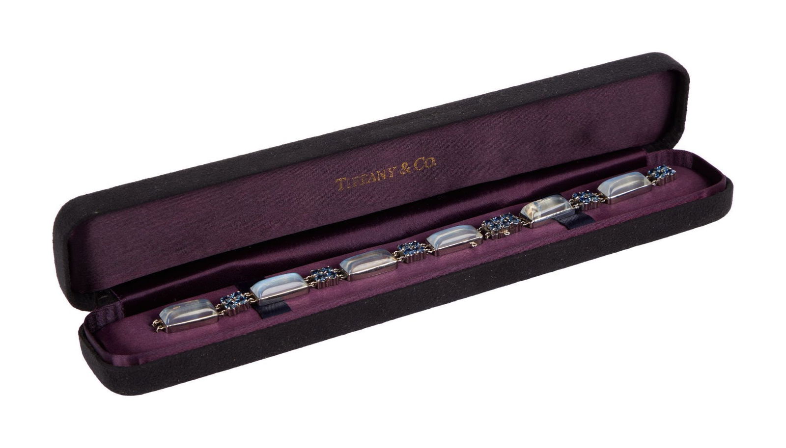Whoopi Goldberg | Tiffany & Co. Platinum Moonstone and Sapphire Bracelet: Designed as a series of elongated rectangular cabochon moonstones, spaced by a four-stone circular-cut sapphire cluster link, 23.0 grams, 6 3/4 inches long, clasp needs repair.Marked Tiffany & Co.Cond
