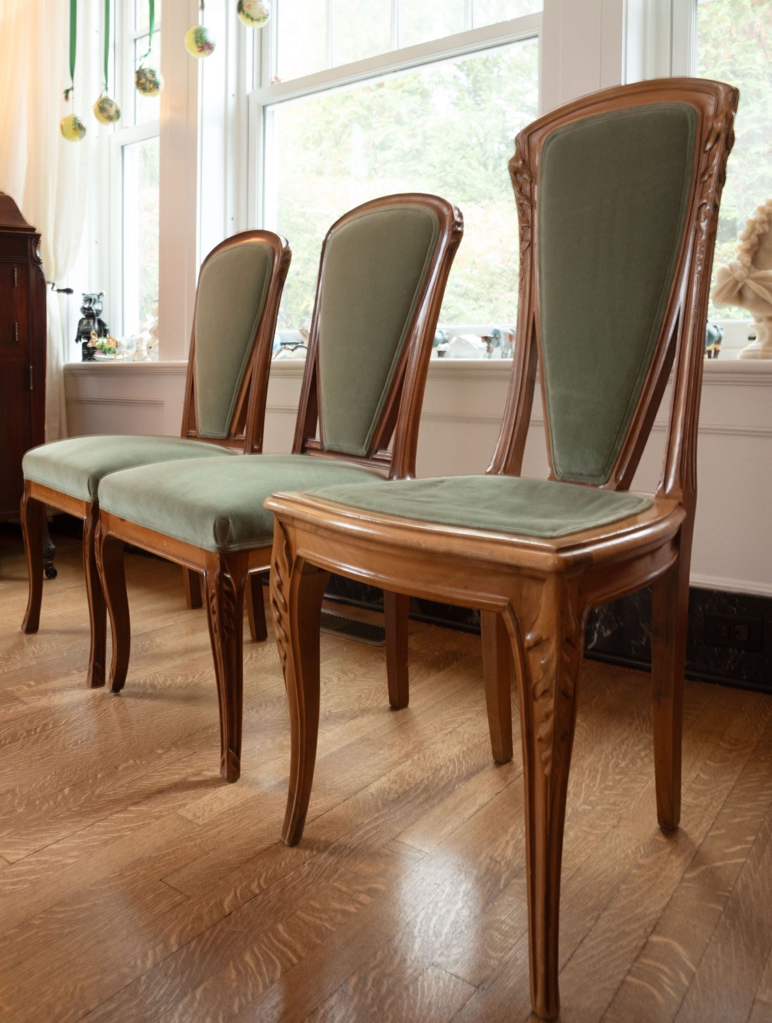 Whoopi Goldberg | Three Louis Majorelle Chicoree Side Chairs: A group of three Art Nouveau carved walnut dining side chairs by Louis Majorelle (French 1859-1926), side chairs in the "Chicorée" (Chickory) pattern, circa 1906, covered in sage velvet upholstery, o