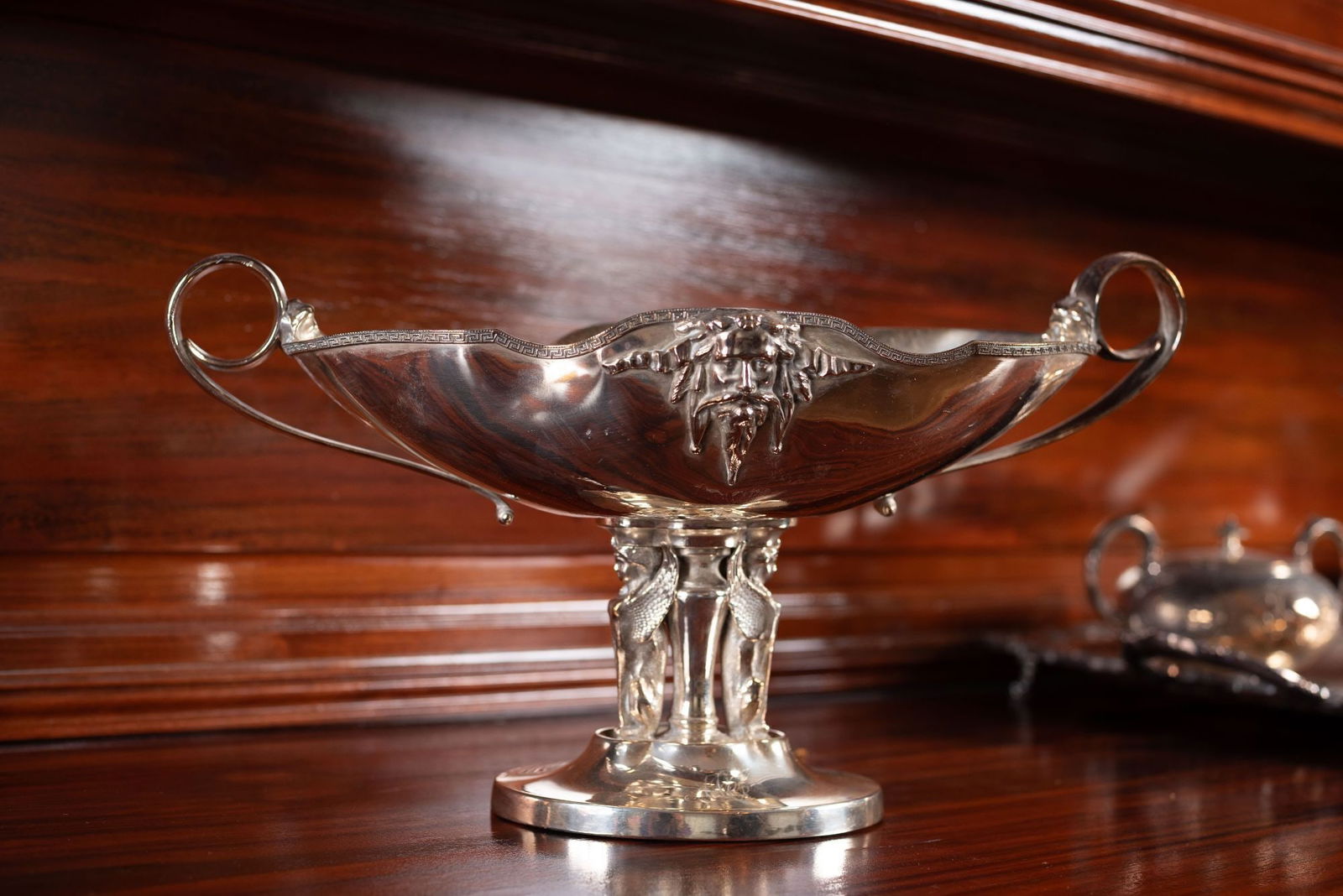 Whoopi Goldberg | Satyr Silver Plated Centerpiece Bowl: An American Classical Revival navette-shaped centerpiece bowl decorated with a satyr visage and tripod sphinx supports atop a circular base. Marked "Triple Plate" on the underside. 9.5 x 16 x 8 inches